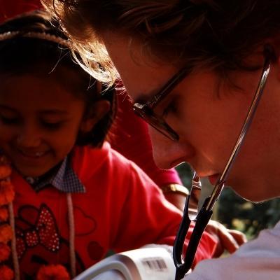 Female student on nursing internship in Nepal checking a child with a stethoscope. A female intern from Projects Abroad is pictured treating a child using a stethoscope on her nursing intership in Nepal.